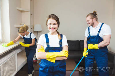 在工作過程中使用專業(yè)設備的清潔服務。專業(yè)的小廚房清潔, 沙發(fā)干洗, 窗戶和地板清洗。穿制服、工作服和橡膠手套的男人和女人